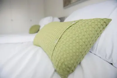 a green pillow sitting on top of a white bed at Mowbray Quarters of Cambridge in Cambridge
