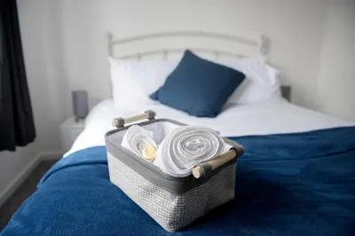 a basket of towels sitting on top of a bed at Mowbray Quarters of Cambridge in Cambridge