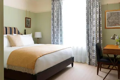 a bedroom with a bed and a desk and a window at University Arms, Autograph Collection in Cambridge