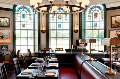 a dining room with tables and stained glass windows at University Arms, Autograph Collection in Cambridge