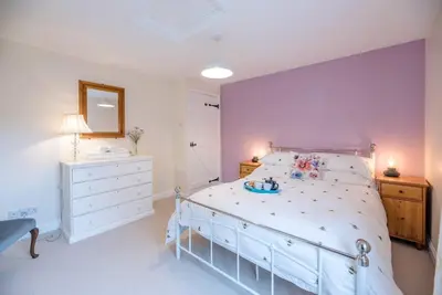a bedroom with a large white bed and a mirror at No. 10, The Cottage in Framlingham