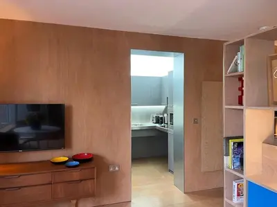 a living room with a flat screen tv and a kitchen at Seahorse Studio, Aldeburgh in Aldeburgh