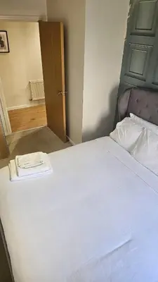 a bedroom with a large white bed with a wooden headboard at The Retreat at Harlow in Potter Street