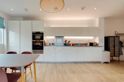a kitchen with white cabinets and a table and chairs at Pass the Keys Stunning and Spacious Modern Flat - Own Car Park in Cambridge
