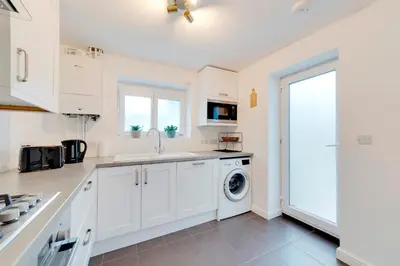 a kitchen with white cabinets and a washer and dryer at Pass the Keys Modern & Spacious 1 Bed Terrace with Free Parking in Cambridge