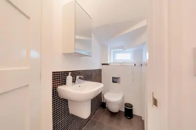 a white bathroom with a sink and a toilet at Pass the Keys Modern & Spacious 1 Bed Terrace with Free Parking in Cambridge