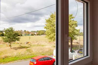 a window with a red car looking out at a field at Pass the Keys 49 Byron Square Modern and Spacious 3 Bed Home with Free Parking in Cambridge
