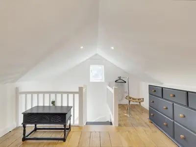 a attic room with a table and a dresser at Pass the Keys 19th Century Barn with Free Parking in Histon