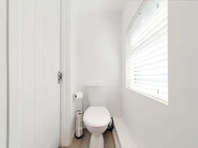 a white bathroom with a toilet and a window at Pass the Keys 19th Century Barn with Free Parking in Histon