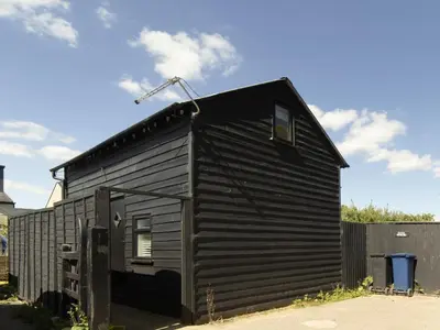 a small black house with a roof at Pass the Keys 19th Century Barn with Free Parking in Histon
