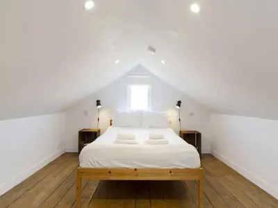 a bedroom with a bed with white sheets and a window at Pass the Keys 19th Century Barn with Free Parking in Histon