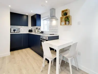 a kitchen with blue cabinets and a white table and chairs at Pass the Keys 19th Century Barn with Free Parking in Histon
