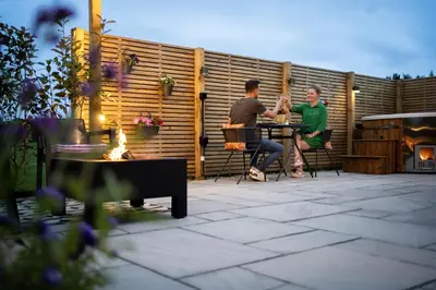 two men sitting at a table in front of a fence at The Huts At Woodthorpes in Assington