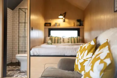 a bedroom with a bed and a couch in a room at The Huts At Woodthorpes in Assington