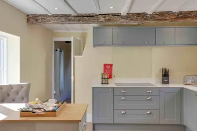 a kitchen with gray cabinets and a wooden table at Josua Medieval Living Maldon in Maldon