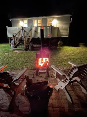 a fire pit in front of a house at night at Muffins Meadow Shepherds Hut in Tillingham