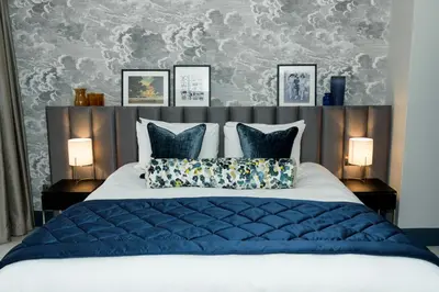 a bedroom with a large bed with blue pillows at Gonville Hotel in Cambridge