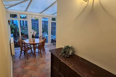 a conservatory with a table and chairs and a glass ceiling at Beautiful Spacious 5 Bed House in Fornham Saint Martin