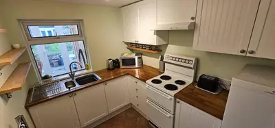 a kitchen with white cabinets and a wooden counter top at Beautiful Spacious 5 Bed House in Fornham Saint Martin
