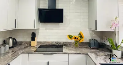 a kitchen with white cabinets and a vase of flowers on the counter at 3 Bedroom House Garden Free Parking 15 min to centre 5 min to motorway in Cambridge