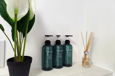 a group of three bottles on a shelf next to a plant at 3 Bedroom House Garden Free Parking 15 min to centre 5 min to motorway in Cambridge