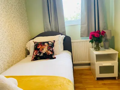 a small bed with a pillow and a vase of flowers at 3 Bedroom House Garden Free Parking 15 min to centre 5 min to motorway in Cambridge
