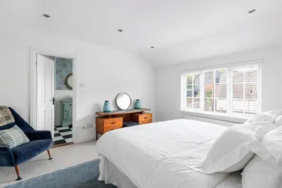 a white bedroom with a bed and a blue chair at Beautiful Apartment Wendens Ambo in Wendens Ambo