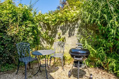 a patio with a grill and two chairs and a table at 1 Bed in Saxmundham oc-c27420 in Farnham