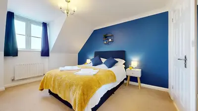 a blue bedroom with a bed and a blue wall at Duxford Deluxe in Thriplow