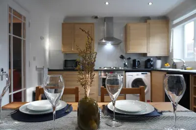 a table with two wine glasses and a vase on it at Duxford Deluxe in Thriplow