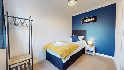 a bedroom with a bed with a blue wall at Duxford Deluxe in Thriplow