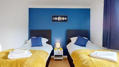 two beds in a room with blue walls at Duxford Deluxe in Thriplow