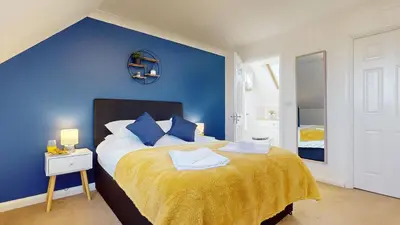 a blue bedroom with a bed with a yellow blanket at Duxford Deluxe in Thriplow