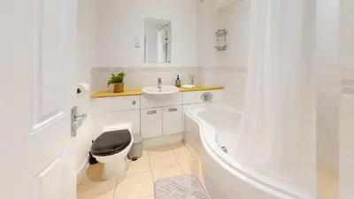a white bathroom with a sink and a toilet and a tub at Duxford Deluxe in Thriplow