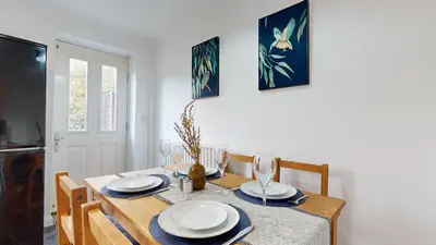 a dining room table with plates and glasses on it at Duxford Deluxe in Thriplow
