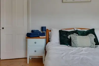 a bed with green pillows next to a night stand at Roman Cottage Chelmsford in Chelmsford