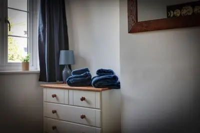 a bedroom with blue towels on a dresser with a window at Roman Cottage Chelmsford in Chelmsford