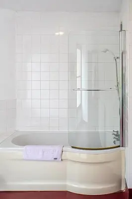 a white bathroom with a shower and a tub at The George Hotel in Chatteris