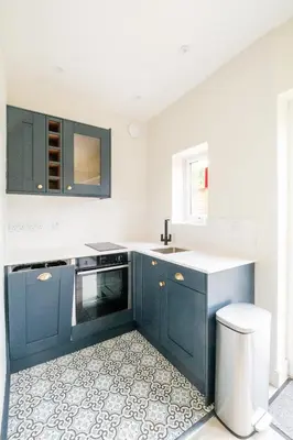 a kitchen with blue cabinets and a white counter top at Hole in One in Aldeburgh