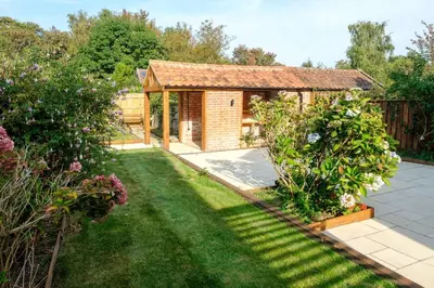 a garden with a small house with a lawn at Hole in One in Aldeburgh