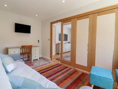 a bedroom with a bed and a desk and a television at Wellington Cottage in Ely