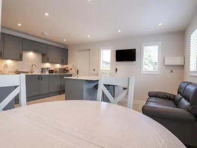 a kitchen and living room with a table and a couch at Wellington Cottage in Ely