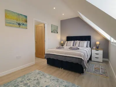 a bedroom with a large bed and a staircase at Wellington Cottage in Ely