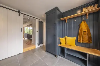 a hallway with blue walls and a bench with yellow pillows at Granary Cottage in Wenhaston