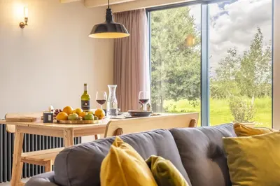 a living room with a couch and a table with wine glasses at Granary Cottage in Wenhaston