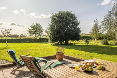 a table with a bowl of fruit and chairs on a patio at Granary Cottage in Wenhaston