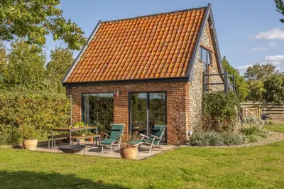 a small brick cottage with a table and chairs at Granary Cottage in Wenhaston