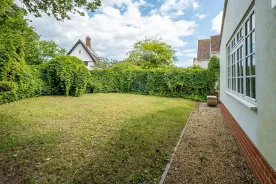 a yard next to a house with a hedge at Salt Cellar Cottage, Aldeburgh - Aldeburgh Coastal Cottages in Aldeburgh