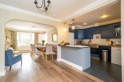 a kitchen and dining room with blue cabinets and a table at Salt Cellar Cottage, Aldeburgh - Aldeburgh Coastal Cottages in Aldeburgh