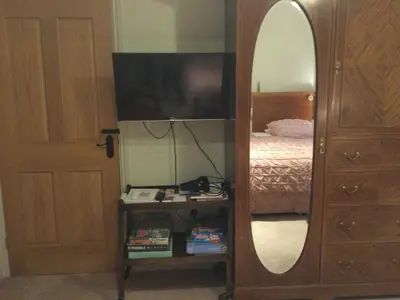 a bedroom with a mirror and a bed and a dresser at STACK YARD COTTAGE. in Cambridge